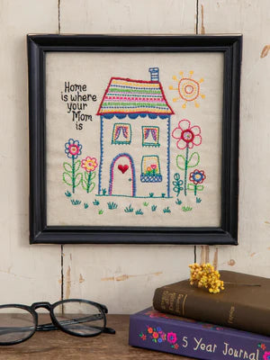 Embroidered wall art Home is where your mom is. Black frame to hang or sit. Flowers, house, and sunshine