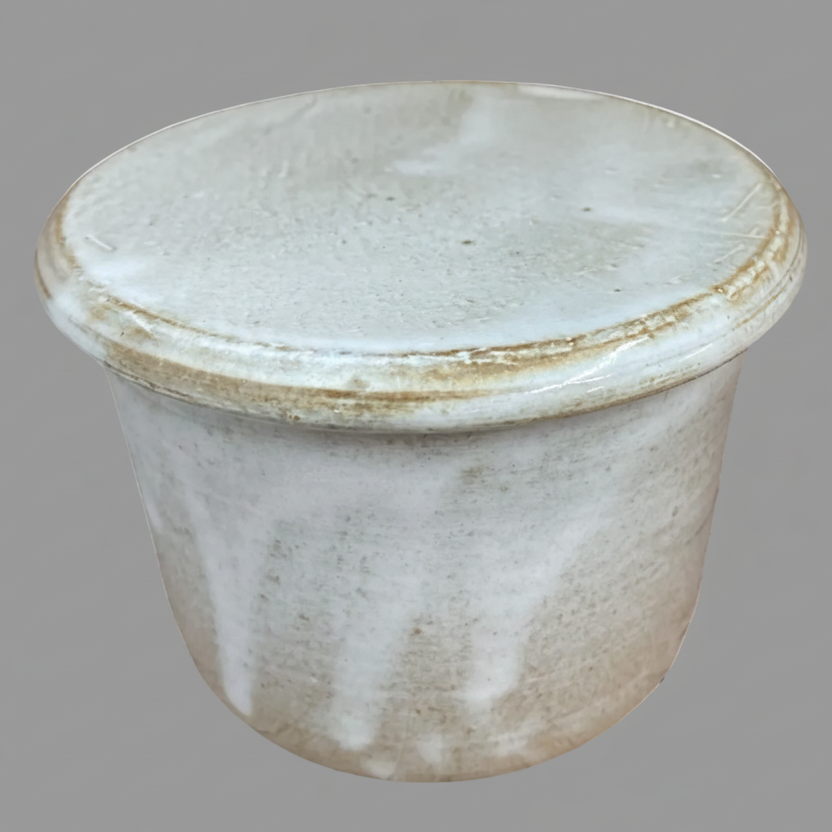 Cylindrical ceramic container with a lid on a gray background